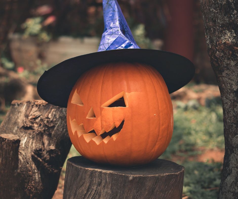 A carved pumpkin is sitting on a piece of wood, wearing a witch hat.