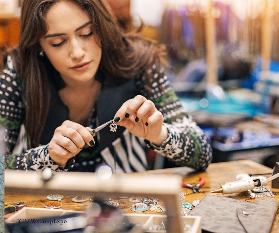 A woman attaches a charm to a cord as she makes fall jewelry. 